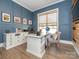 Home office with a large desk, built-in storage, and blue accent wall at 14543 Crosswater Ln, Charlotte, NC 28278