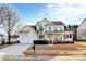 Traditional yellow home with a spacious porch, a manicured lawn, and an attached two-car garage at 15313 Wedgewood Commons Dr, Charlotte, NC 28277