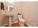 Clean bathroom with pedestal sink, toilet, and hardwood floors at 2510 Oakboro Ln, Charlotte, NC 28214