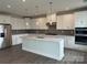 Modern white kitchen with stainless steel appliances, island, and gray backsplash at 7120 Wayfarer Dr # 0079, Charlotte, NC 28269