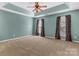 A spacious main bedroom featuring carpet, a tray ceiling, ceiling fan, and large windows at 1027 Fountainbrook Dr, Indian Trail, NC 28079