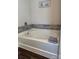 Soaking tub with gray tile surround and a linen shelf at 1112 Culver Spring Way, Charlotte, NC 28215