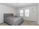 Comfortable bedroom with neutral carpet, a gray upholstered bed frame and two windows at 12849 Robert Walker Dr, Davidson, NC 28036