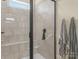 Modern bathroom featuring tiled shower with glass door and bench, and two neutral-toned robes at 200 Staffordshire Dr, Statesville, NC 28625