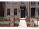 Brick townhome with a black front door, small garden area, and a black iron fence at 216 Gilead Rd, Huntersville, NC 28078