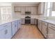 Well-lit kitchen with stainless steel appliances, light wood floors, gray cabinets, and a spacious quartz countertop island at 216 Gilead Rd, Huntersville, NC 28078