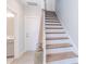 Stairway with wooden treads and white risers and a wooden banister, leading up from the entrance near a bathroom and a door at 216 Gilead Rd, Huntersville, NC 28078