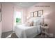 Comfortable pink bedroom featuring a bed with white bedding, decorative pillows, and framed art at 2533 Ellen Ave # 1016B, Charlotte, NC 28208