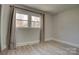 Empty bedroom with neutral walls features a bright window with neutral drapes and light laminate flooring at 2624 Ashley Rd, Charlotte, NC 28208