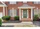 Close-up of a charming brick home's front entrance, showing an elegant green door and manicured landscaping at 561 Ambergate Nw Pl, Concord, NC 28027