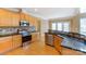 Well-lit kitchen features wood cabinets, stainless steel appliances, and dark countertops at 561 Ambergate Nw Pl, Concord, NC 28027