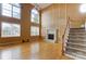 Bright living room features a fireplace, hardwood floors, large windows, and staircase at 561 Ambergate Nw Pl, Concord, NC 28027