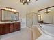 Bright bathroom featuring double vanity, walk-in shower, soaking tub, and elegant lighting at 6042 Legacy Cir, Charlotte, NC 28277