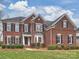 Charming two-story brick home featuring black shutters, a manicured lawn, and professional landscaping at 6042 Legacy Cir, Charlotte, NC 28277