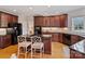 Open kitchen with black appliances, hardwood floors, kitchen island with seating and dark wood cabinets at 6042 Legacy Cir, Charlotte, NC 28277