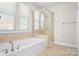 Relaxing bathroom with soaking tub, glass shower, and neutral tile at 6361 Willow Farm Dr, Denver, NC 28037