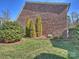 Brick home with a lawn featuring an evergreen bush, trees, and a well maintained lawn at 712 English Tudor Ln, Charlotte, NC 28211