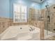 Bathroom featuring a glass-enclosed shower and a luxurious soaking tub at 712 English Tudor Ln, Charlotte, NC 28211