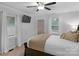 A bright bedroom has two windows, a wall-mounted TV, and a bed with white linens and a quilted gold throw at 725 Plantation Rd, Lancaster, SC 29720