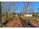 A white house with a brick chimney and a large front yard covered with leaves and mature trees at 725 Plantation Rd, Lancaster, SC 29720