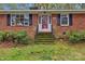 Charming red brick home featuring stairs leading up to the entry door at 725 Plantation Rd, Lancaster, SC 29720