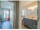 Hallway view to a bathroom featuring a double sink vanity, toilet, and a window for natural light at 7505 Torphin Ct, Charlotte, NC 28269