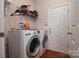 Bright laundry room featuring a modern washer and dryer, shelving and wood look floor at 12016 Regent Ridge Ln, Charlotte, NC 28278