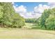 Picturesque view of a green golf course with mature trees and blue sky with clouds in the background at 12104 Baywoods Dr, Tega Cay, SC 29708