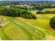 Aerial view of a golf course featuring a driving range, lush green fairways, and a scenic lake at 12104 Baywoods Dr, Tega Cay, SC 29708