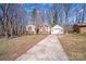 View of the house and the detached garage with long driveway surrounded by woods at 3029 Winding Trl, Matthews, NC 28105