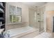 Bright bathroom featuring a soaking tub, a glass-enclosed shower, and a shuttered window at 3421 Walston Ln, Charlotte, NC 28211