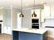 Modern kitchen with white cabinets, a blue island, and gold pendant lights at 553 W Lowrance Ave, Mooresville, NC 28115