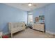 Bright bedroom features a white crib, matching dresser, and light blue walls at 7219 Yellowhorn Trl, Waxhaw, NC 28173