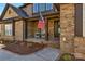 Inviting covered front porch with American flag, seating, and neatly landscaped garden at 7219 Yellowhorn Trl, Waxhaw, NC 28173