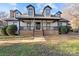 Two-story white brick home with black accents, a front porch, and landscaping at 8478 Rocky River Rd, Harrisburg, NC 28075