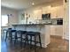 Open-concept kitchen featuring white cabinets, stainless steel appliances, and bar seating at 104 Sycamore Crossing Ct, Locust, NC 28097