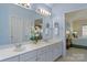 Well-lit bathroom featuring dual sinks, a large mirror, and a glimpse into an adjoining bedroom at 10417 Sutherby Dr, Charlotte, NC 28277