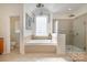 Bright bathroom showcasing a soaking tub beneath a window and a glass-enclosed shower with tiled walls at 1806 Grayscroft Dr, Waxhaw, NC 28173