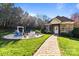 Charming brick home with a stone path leading to a fire pit and seating area in a landscaped backyard at 4008 Quintessa Dr, Matthews, NC 28104