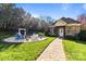 Landscaped backyard featuring a fire pit area with seating, pergola, and lush greenery at 4008 Quintessa Dr, Matthews, NC 28104