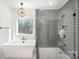 Spa bathroom featuring a soaking tub, glass-enclosed shower with gray tile, and elegant lighting at 4605 Western Union School Rd, Waxhaw, NC 28173