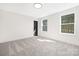 A bedroom with neutral carpet, white walls, two windows, and a gray accent door at 4605 Western Union School Rd, Waxhaw, NC 28173