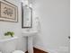 Modern powder room with pedestal sink, framed mirror, and hardwood floors at 523 Rock Skip Way, Fort Mill, SC 29708