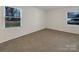 Well-lit bedroom with neutral carpeting and two windows at 7015 Cardigan Ave, Charlotte, NC 28215