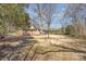 Spacious backyard with dormant grass and scattered trees with an outbuilding on the right at 821 Greentree Dr, Charlotte, NC 28211