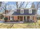 Traditional two-story brick home with a covered front porch, mature landscaping, and a well-manicured lawn at 821 Greentree Dr, Charlotte, NC 28211