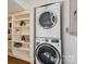 Practical laundry area with stacked washer/dryer and built-in storage shelves at 821 Greentree Dr, Charlotte, NC 28211