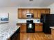 Well-lit kitchen featuring wooden cabinets, granite countertops and black appliances at 9613 Long Hill Dr, Charlotte, NC 28214