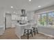 Well-lit kitchen features a center island with bar seating, stainless vent hood, and quartz countertops at 12325 Parks Farm Ln, Charlotte, NC 28277