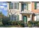 Close-up of townhome exterior featuring well-manicured shrubs and bright green door and shutters at 12584 Jessica Pl, Charlotte, NC 28269